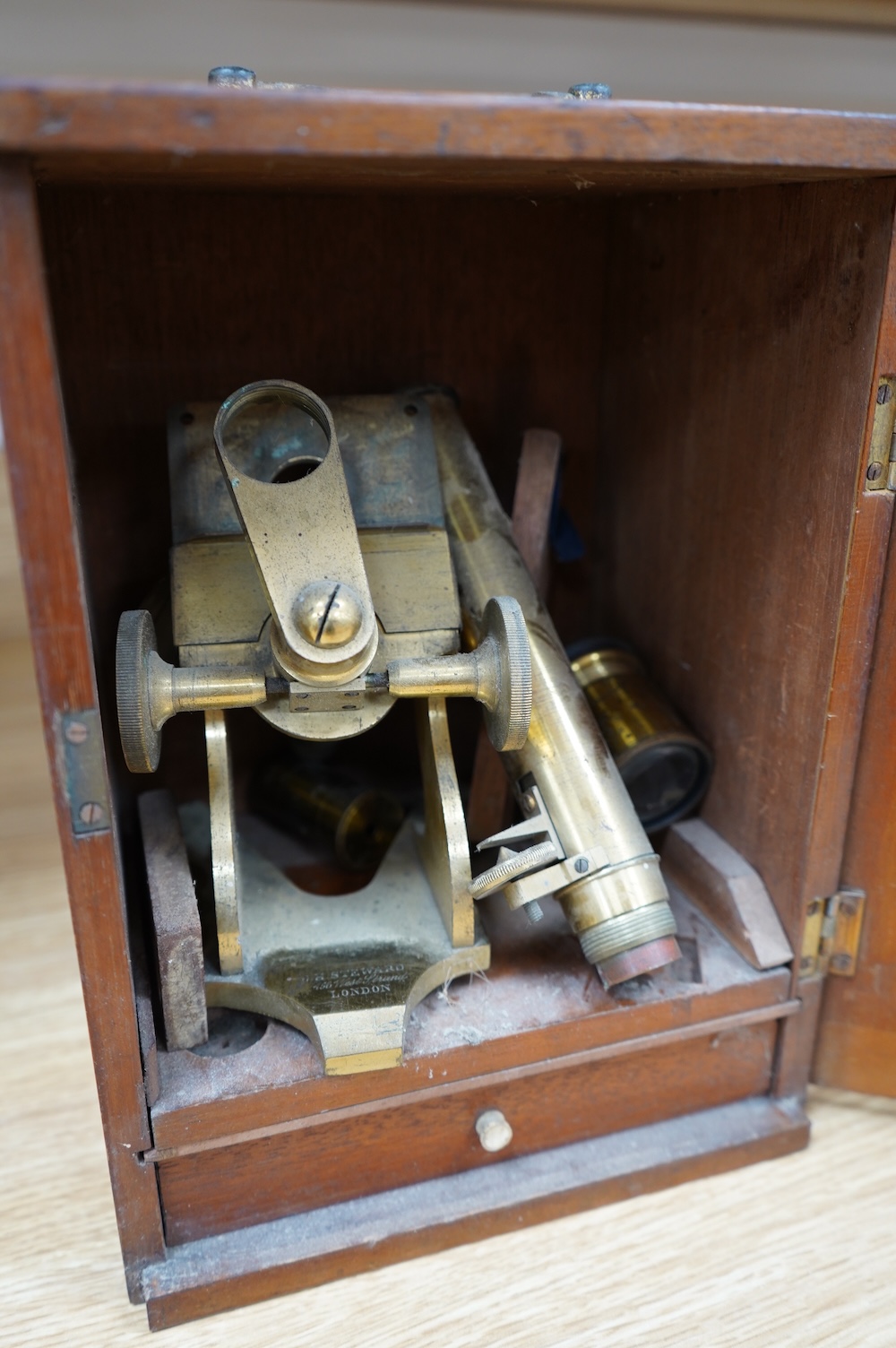 A mahogany cased late 19th century brass microscope by J.H. Steward, 456 West Strand London, with a drawer underneath containing a few prepared microscope slides, case 27cm high, 19.5cm wide, 15.5cm deep. Condition - poo